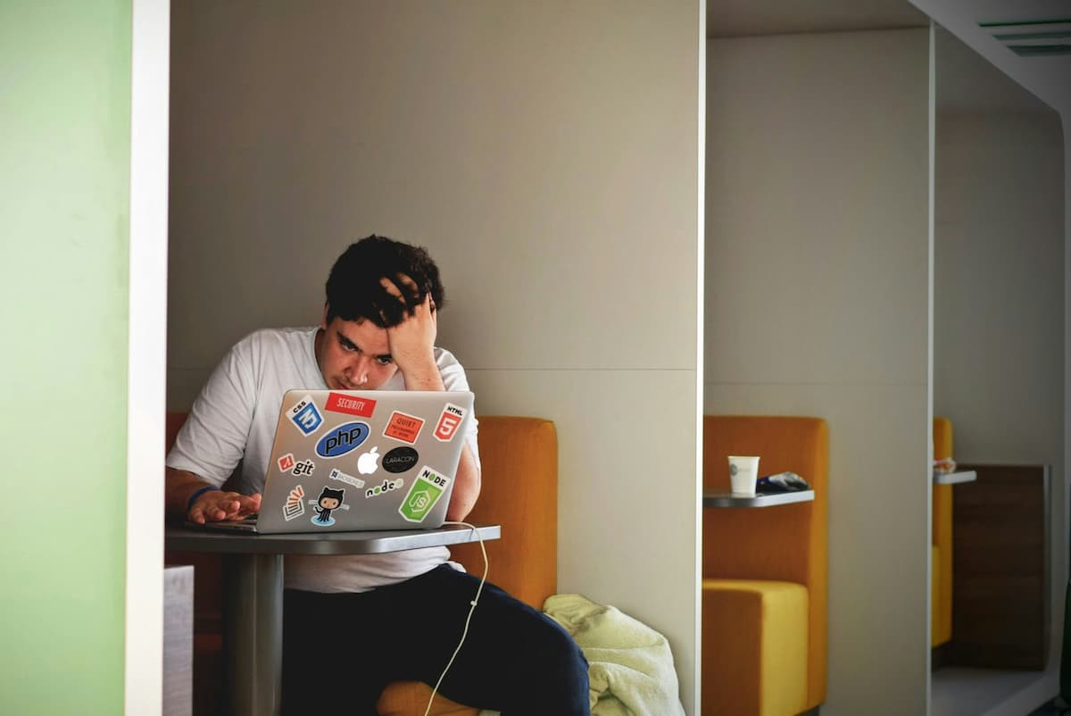 Um garota com a mão na cabeça, lendo em um notebook.